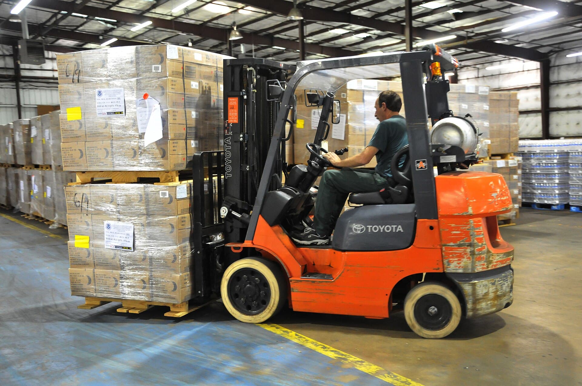 A forklift moving palletized boxes inside a warehouse